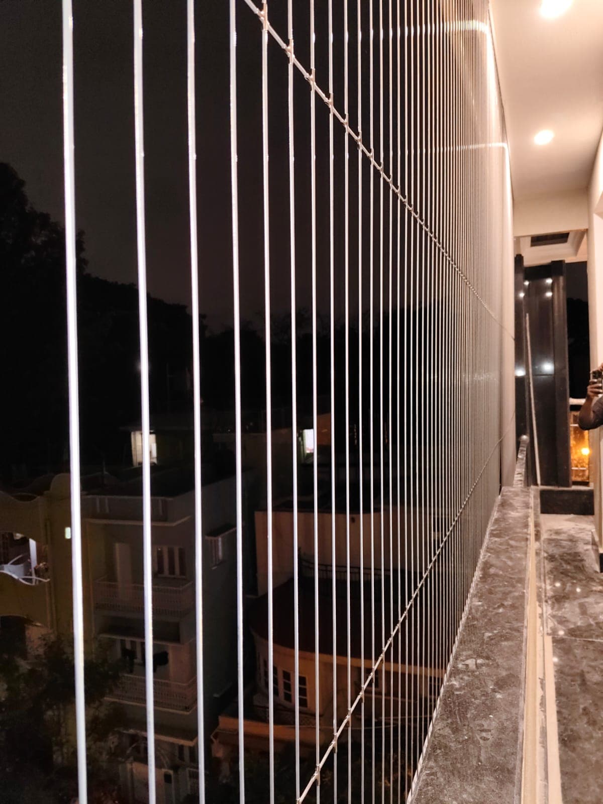 Sleek stainless steel invisible safety grill cables mounted vertically on large balcony windows - AJ Safe Net Solutions